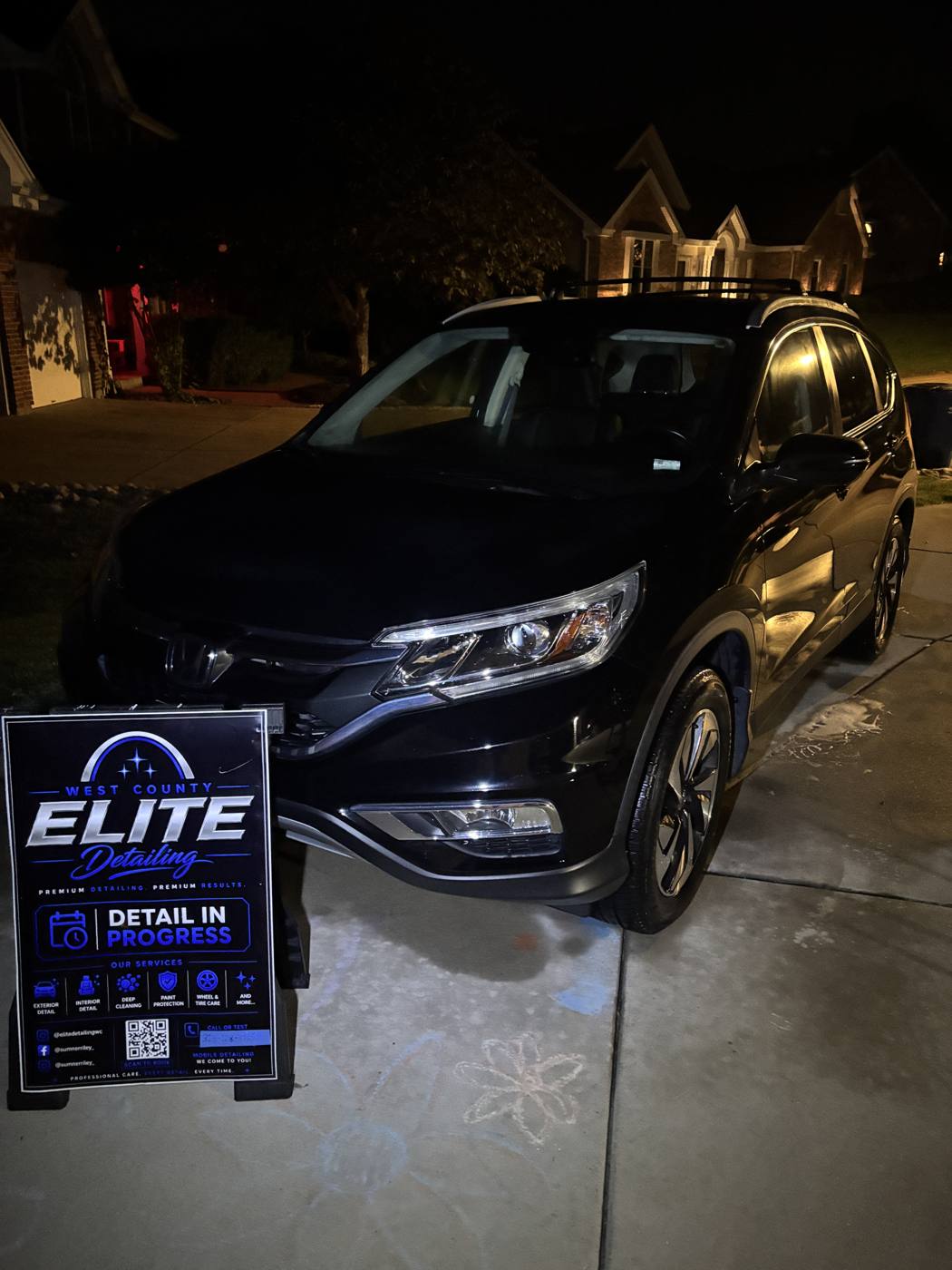 Honda CR-V freshly detailed at night beside the Elite Detailing sign