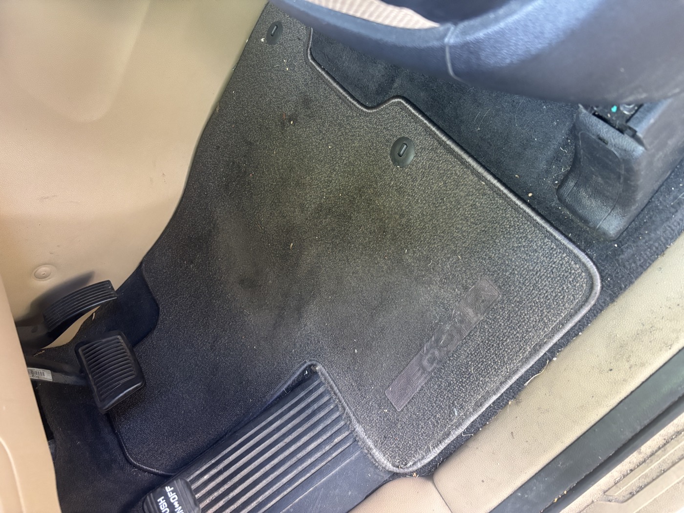 Driver floor mat covered in dirt and debris before detailing