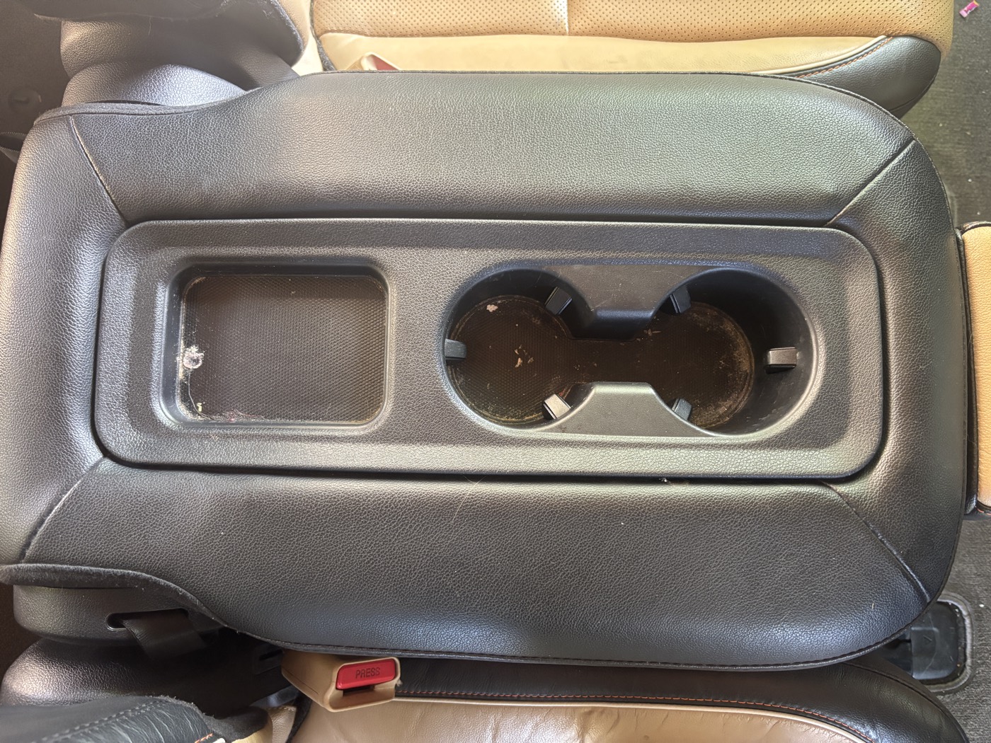 Rear seat cup holder console covered in grime before detailing